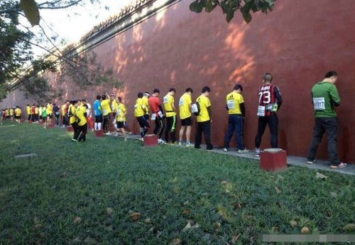 20日，2013年北京马拉松开赛。今年共有超过3万人报名参赛，到哪如厕成了一个焦点。一组众选手站在墙边小便照片在网上风传，选手站成一排，在沿途的红墙和绿化带“就地解决”，地面上“水”流一片。（图片来源：中国青年网）