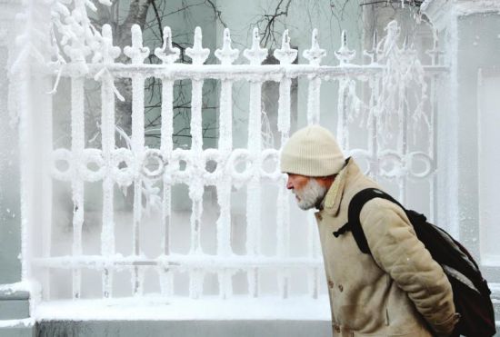 12月19日，在俄罗斯首都莫斯科，一名男子经过一处结满冰霜的栅栏